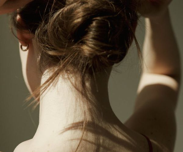 Woman feeling serene with soft green light illuminating her neck and shoulders.